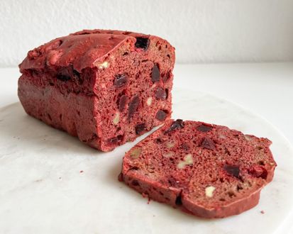 Rote-Bete-Brot mit Walnusskernen Ein aufgeschnittenes Laib Rote-Bete-Brot mit einer Scheibe davor.