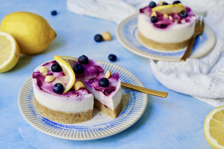 Seitliche Ansicht auf Lemon Cheesecake mit Blaubeeren und Macadamia-Boden