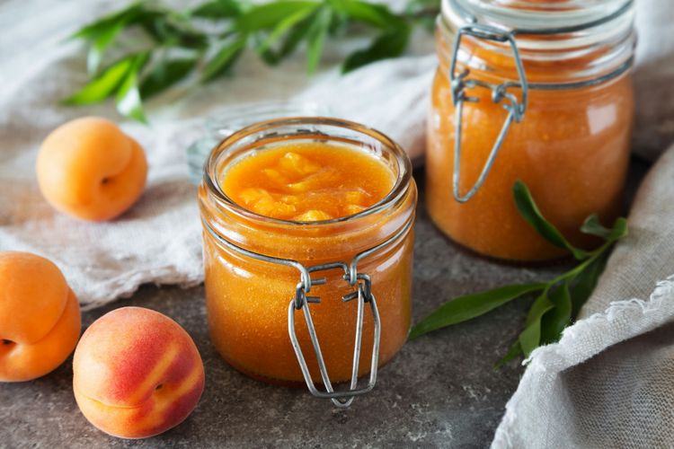 Aprikosenmarmelade im Einmachglas mit Aprikosen angerichtet Aprikosenmarmelade im Einmachglas mit Aprikosen angerichtet