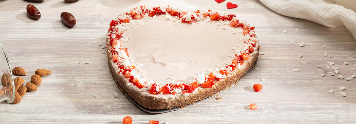 Ein Veganer Cheesecake in Herzform auf einem hellem Untergrund Ein Veganer Cheesecake in Herzform auf einem hellem Untergrund